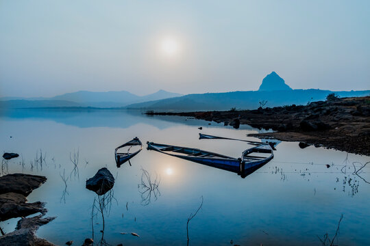 A serene camping setup by the calm waters of Pawna Lake, with tents glowing in the twilight near Lonavala.