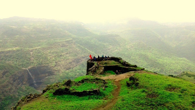 Tourists enjoying the breathtaking sunset view from Rajmachi Point, overlooking the verdant valleys of Khandala.