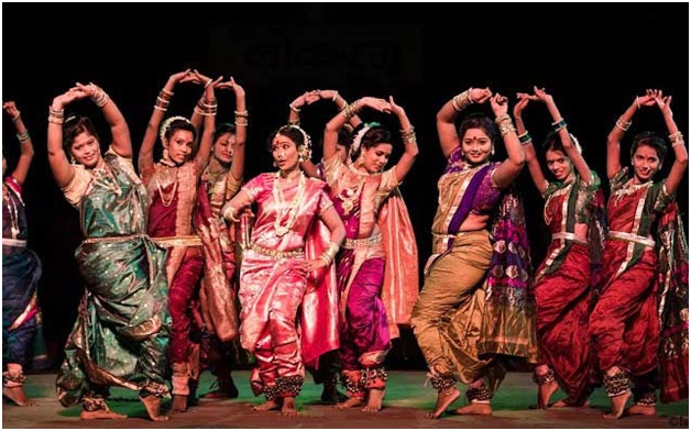 A vibrant Tamasha folk performance featuring dancers and live musicians on a traditional stage setup.
