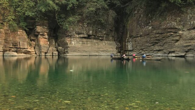 Sunlight filtering through clouds onto the transparent waters of Umngot River, showing pebbles below the surface, Dawki