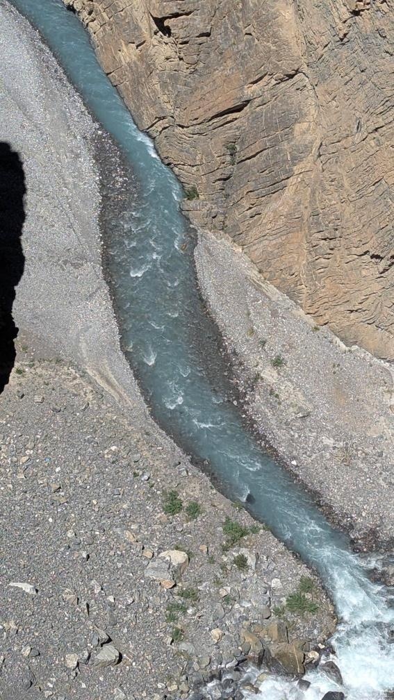 Bird's eye view of a turquoise glacial river winding through a deep rocky gorge with layered canyon walls in the Spiti-Kinnaur region
