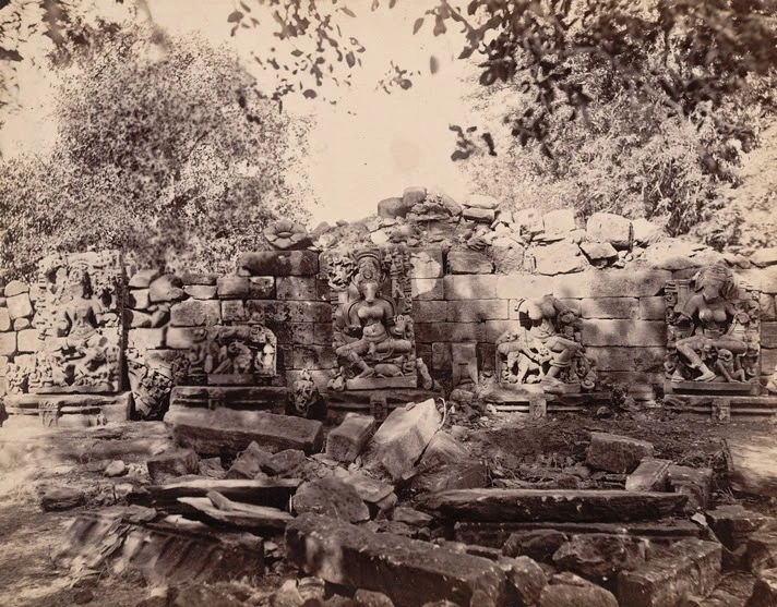 19th century archival photograph of ruined temple wall with carved deity sculptures and scattered stone debris at Bhedaghat, taken during Cunningham's survey