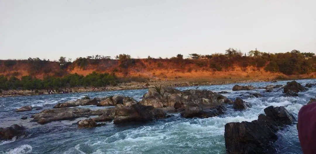 Rocky rapids of the Narmada River at Bhedaghat at sunset with orange and red cliffs visible on the far bank