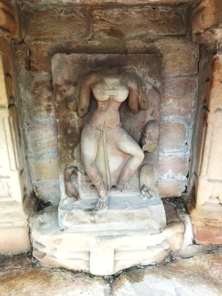 Headless Post Gupta period Yogini sculpture in a niche at Chausath Yogini Temple Bhedaghat, carved in red sandstone with transparent drapery detail